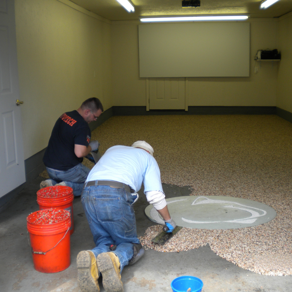 Installers applying the EverStone decorative stone system to a garage floor using hand trowels.