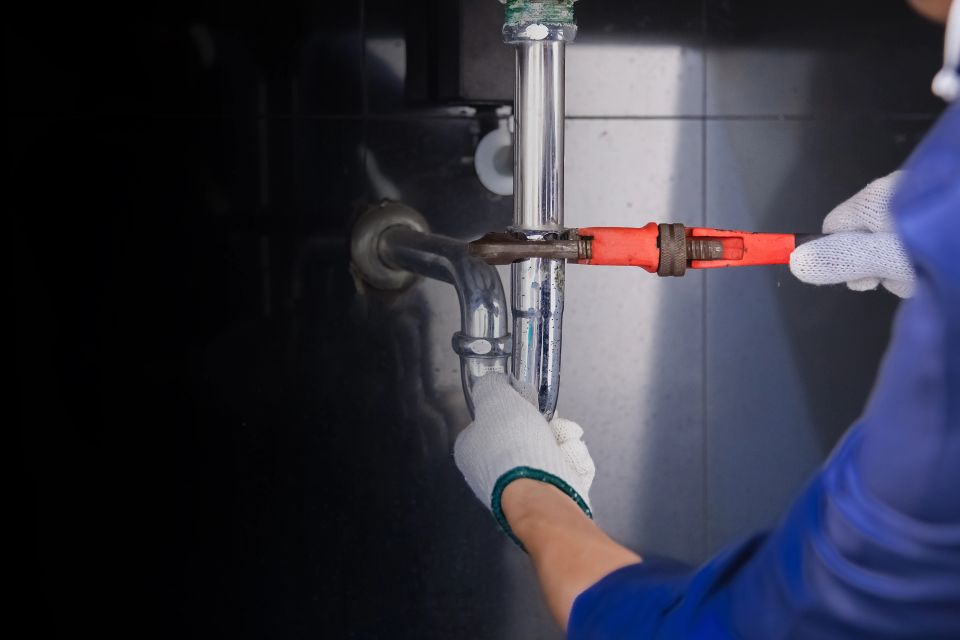 A plumber fixing pipes with a wrench