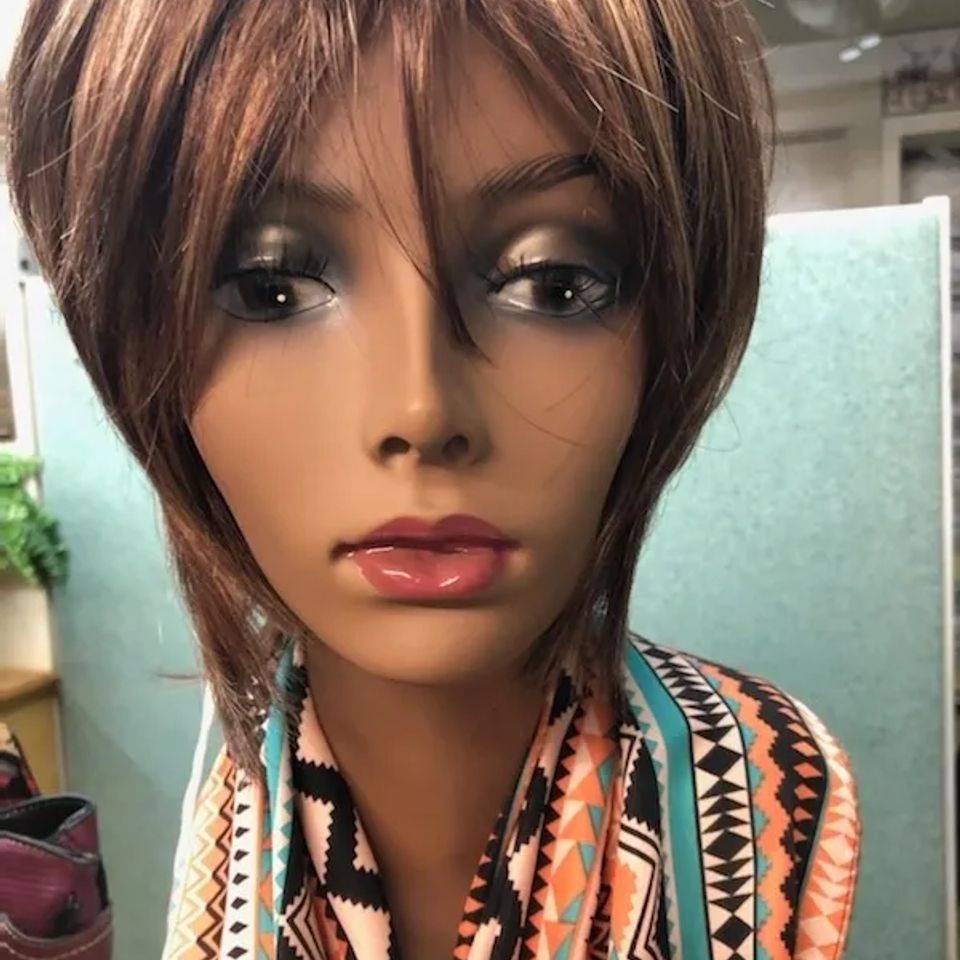 Short layered brown wig displayed on a mannequin, featuring a natural style with side-swept bangs and soft texture.