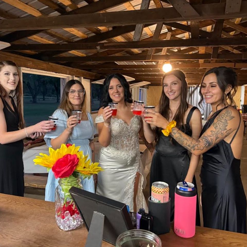 Bride with wedding guests holding drinks at the full bar during the reception