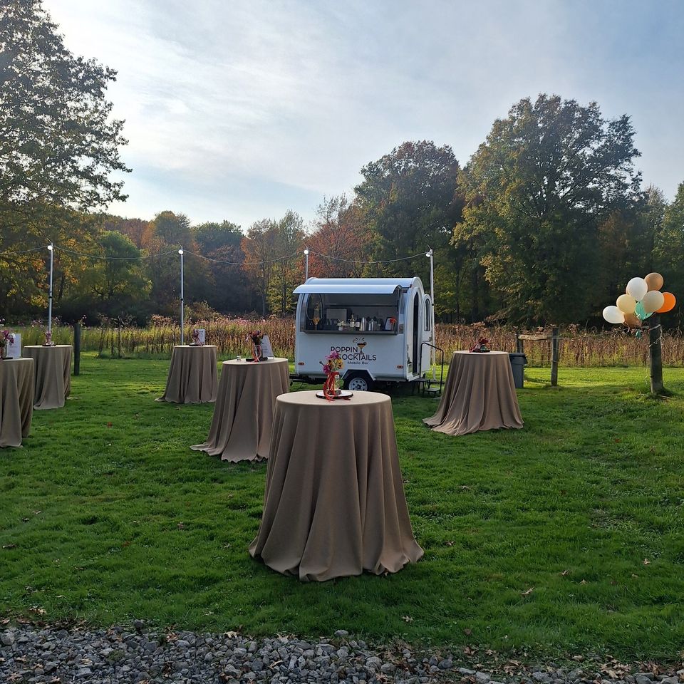 Outdoor setup with cocktail tables and Poppin Cocktails trailer bar 