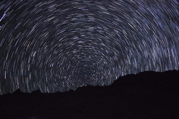 A slow exposure photo of the night sky showing the spinning of the earth 