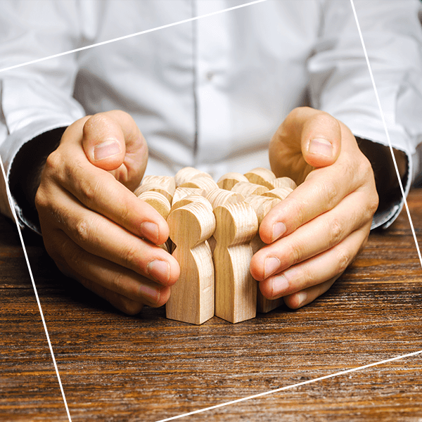 Hands cupped around wooden figures of people