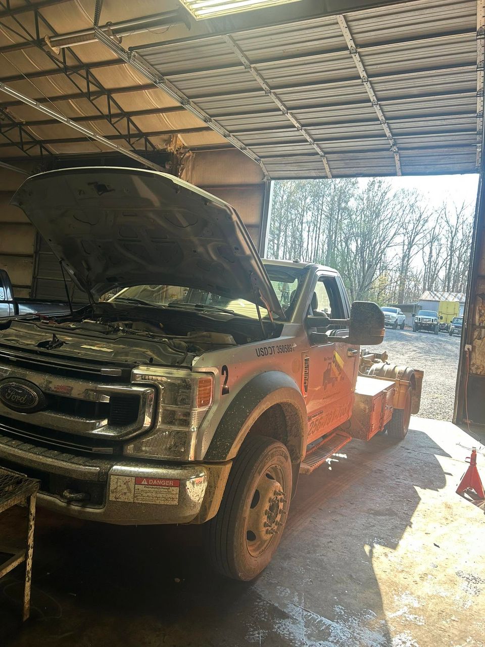 Ford F-550 tow truck with hood open inside diesel repair shop in Arab Alabama