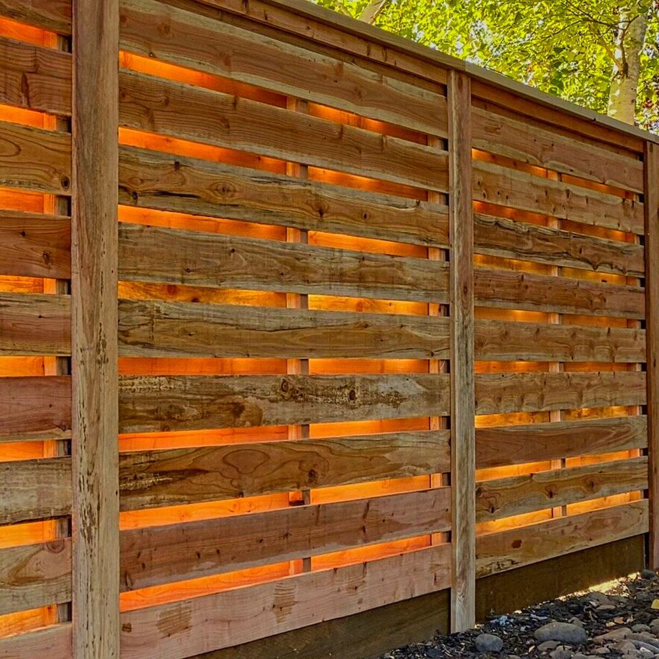 Professionally installed horizontal wood fence with sunlight passing through slats
