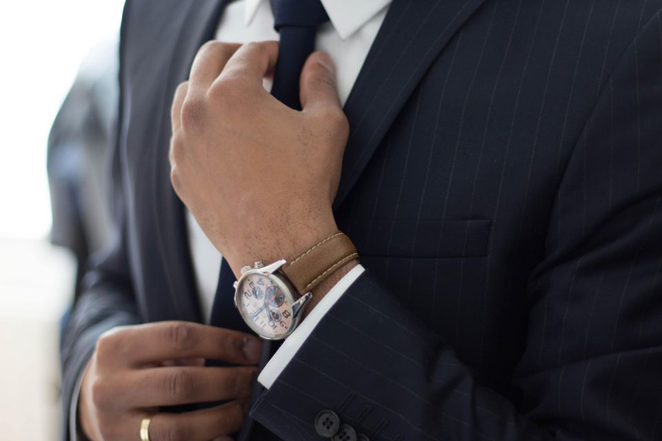 Man fixing his tie on his suit wearing a watch