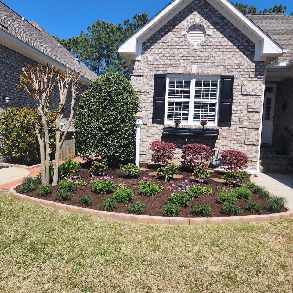 Landscape Design with Plants and Flowers in front of a brick home.