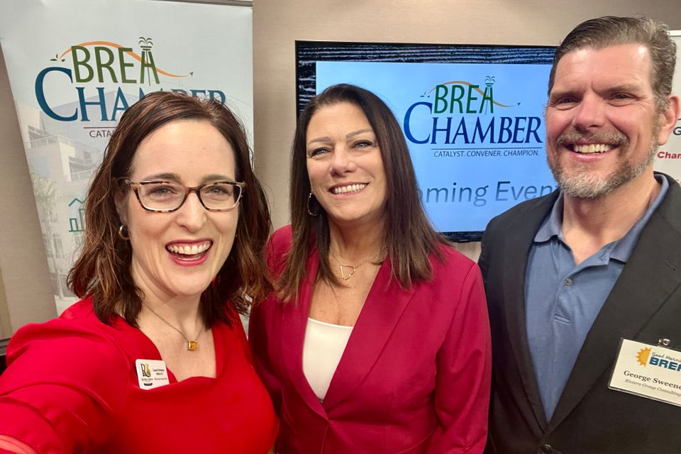 Two women and a man posing at an event