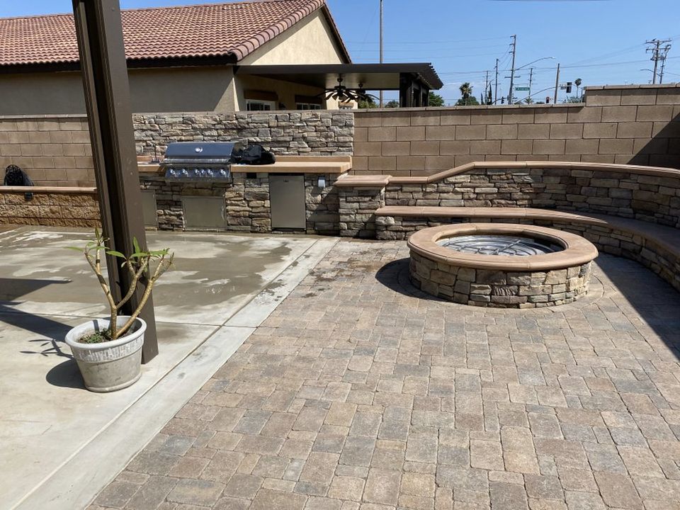 Backyard paver patio with fire pit, outdoor kitchen, and curved seating wall