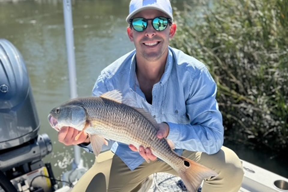 Smiling angler holding a redfish caught on an inshore fishing charter in Charleston, SC