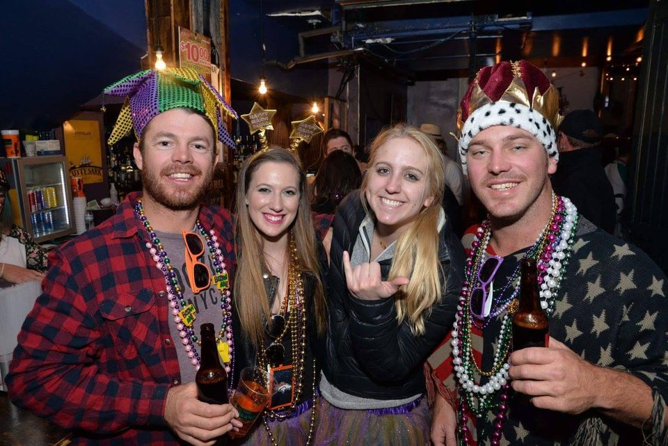 Guests celebrating at a Carpe Diem Events Mardi Gras balcony party wearing beads and festive costumes inside the Bourbon Street venue.
