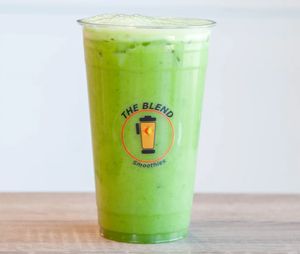 A clear cup filled with bright green juice labeled "The Blend Smoothies," representing a mix of apple, cucumber, kale, celery, and lemon, with a fresh and healthy appearance.