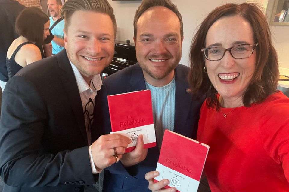 Woman and two men holding journals for photo