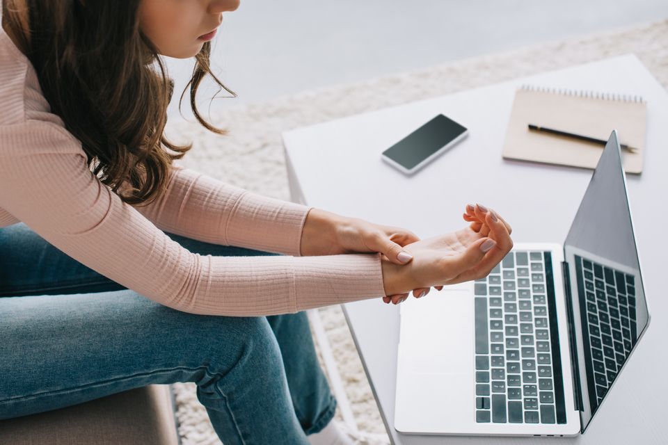 Cropped shot of woman having pain in wrist while using laptop