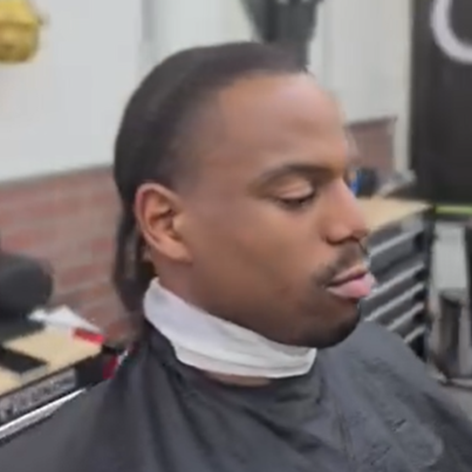 Client receiving a taper haircut with braids tied back at Bronx NY barbershop Jeff Barber Services