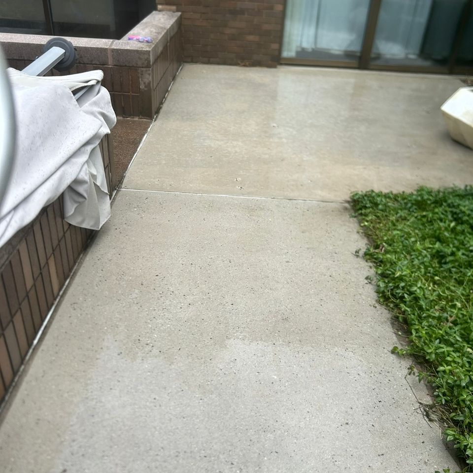 Clean concrete patio beside brick home exterior after pressure washing in Harrisburg PA