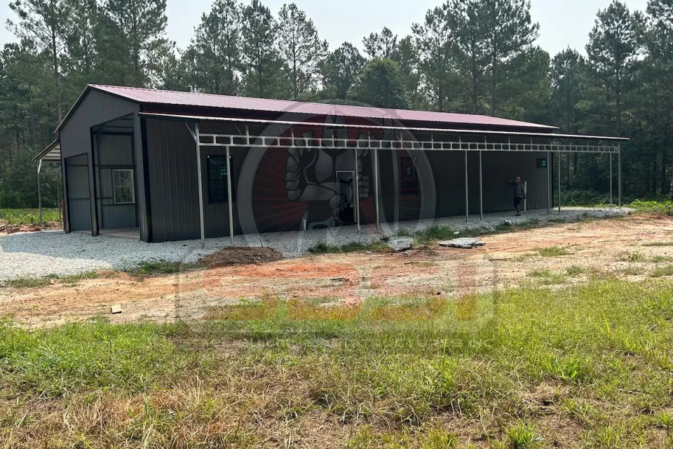 Gray and red steel barn with side lean tos on wooded lot with SBSI watermark representing steel barns in Alabama