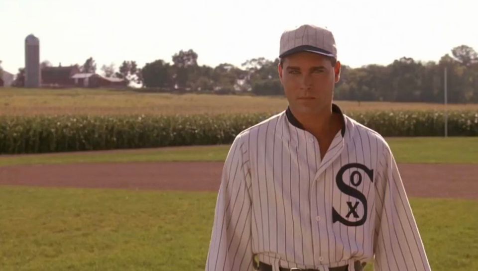 Ray Liota in the movie Field of Dreams with the corn field in the background and him wearing a "Sox" jersey and hat 