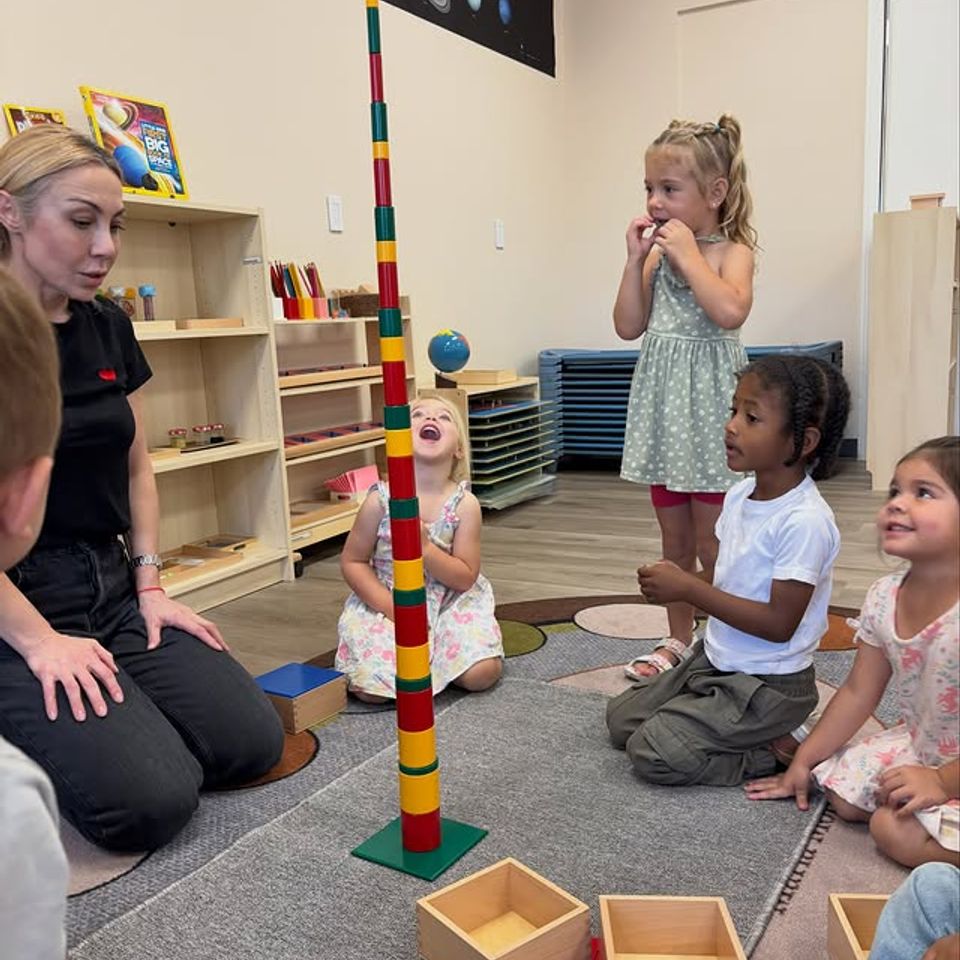 Teacher and preschoolers building a tall Montessori bead stair tower during group lesson time in Palmdale CA