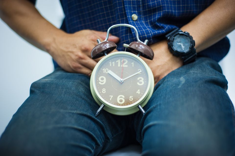 Man holding a large clock on his lap symbolizing erectile dysfunction and timing related sexual health concerns