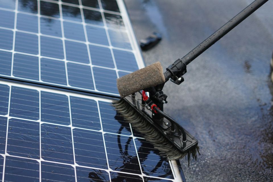 Water-fed brush cleaning wet solar panels during professional solar panel cleaning