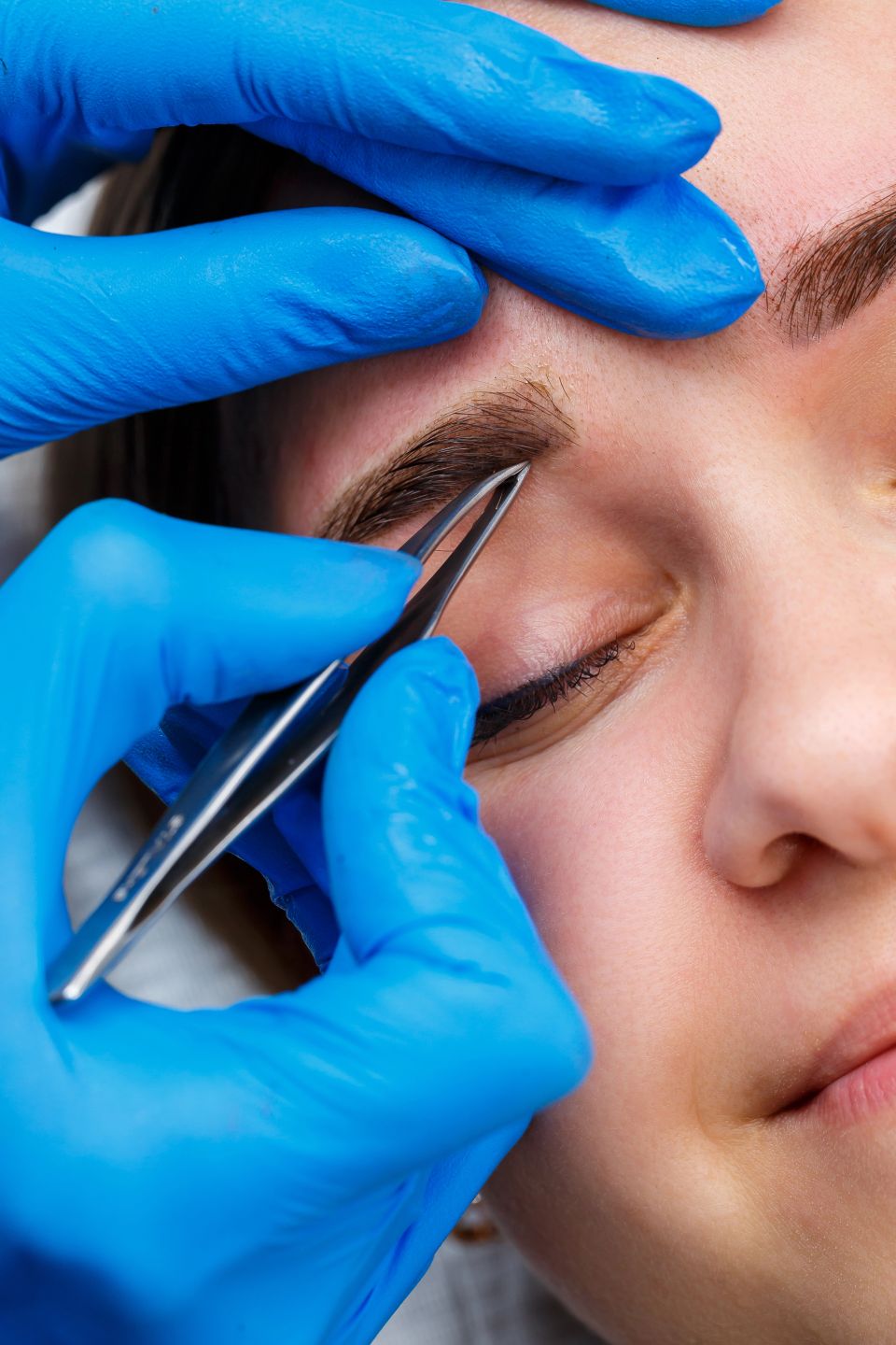 The master plucks out the excess hairs on the eyebrows with tweezers, giving them a shape