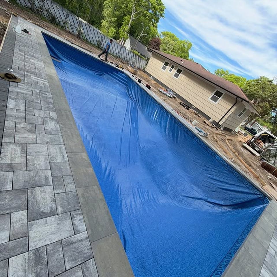 New blue liner set in a rectangular inground pool with gray paver decking in Long Island NY