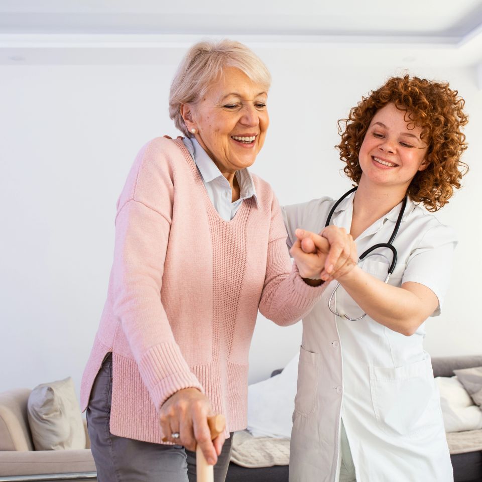 Smiling nurse helping senior lady to walk around the nursing home.