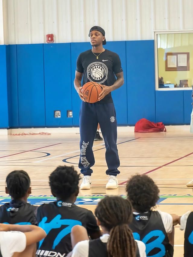 Xavier Allen holding a basketball teaching to a group