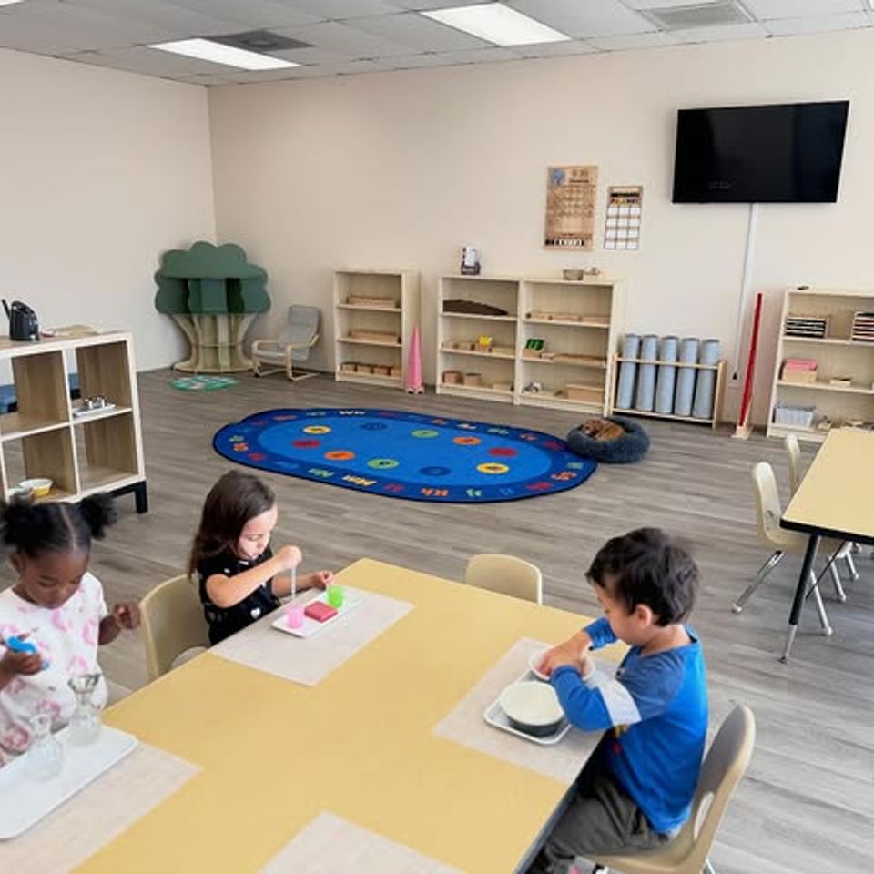 Preschool students seated at work tables in a bright Montessori daycare classroom in Palmdale CA