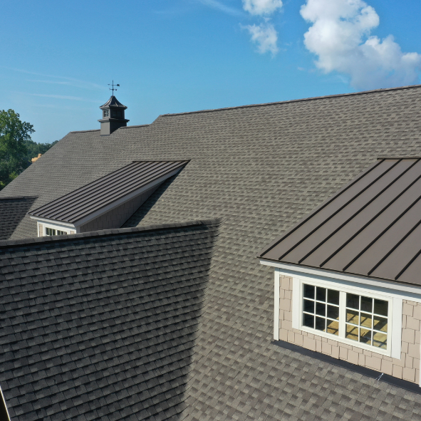 Home with a combination of architectural asphalt shingles and standing seam metal roofing installed by E & D Roofing, Inc.