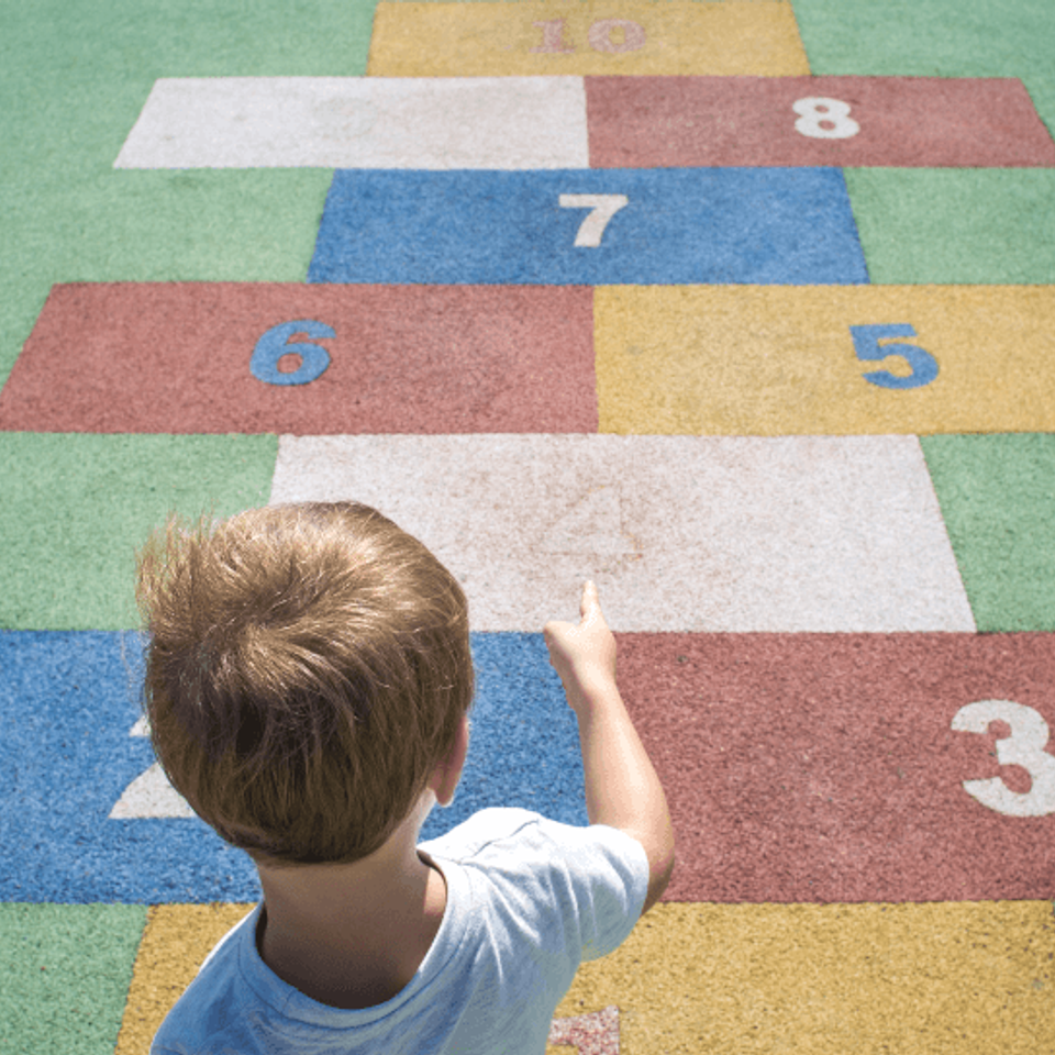 Child standing on a colorful EverStone Flex hopscotch play surface.