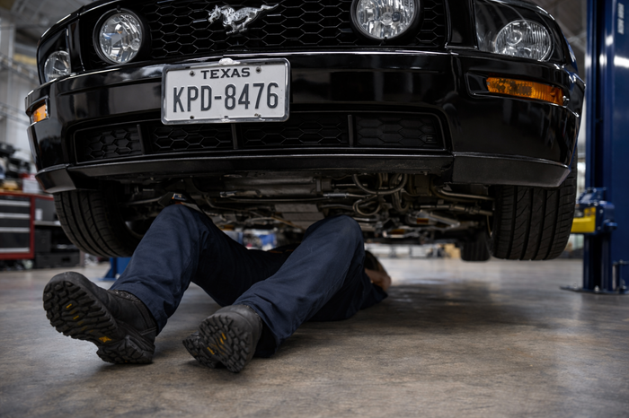 Mechanic working beneath a Ford Mustang GT during tune-up and undercar service in Missouri City, TX