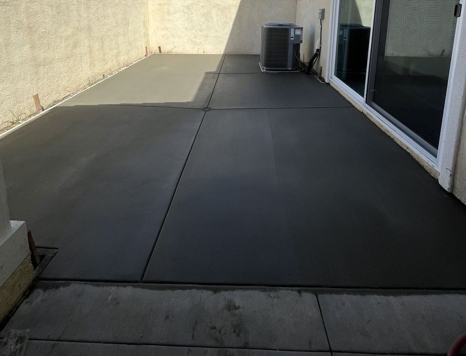 Newly installed concrete patio adjacent to residential backyard home