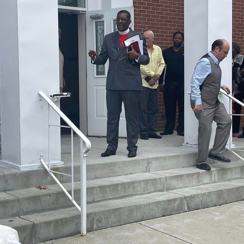 Church leaders and congregants standing outside the entrance of Grace Evangelistic Temple Church after a worship service.