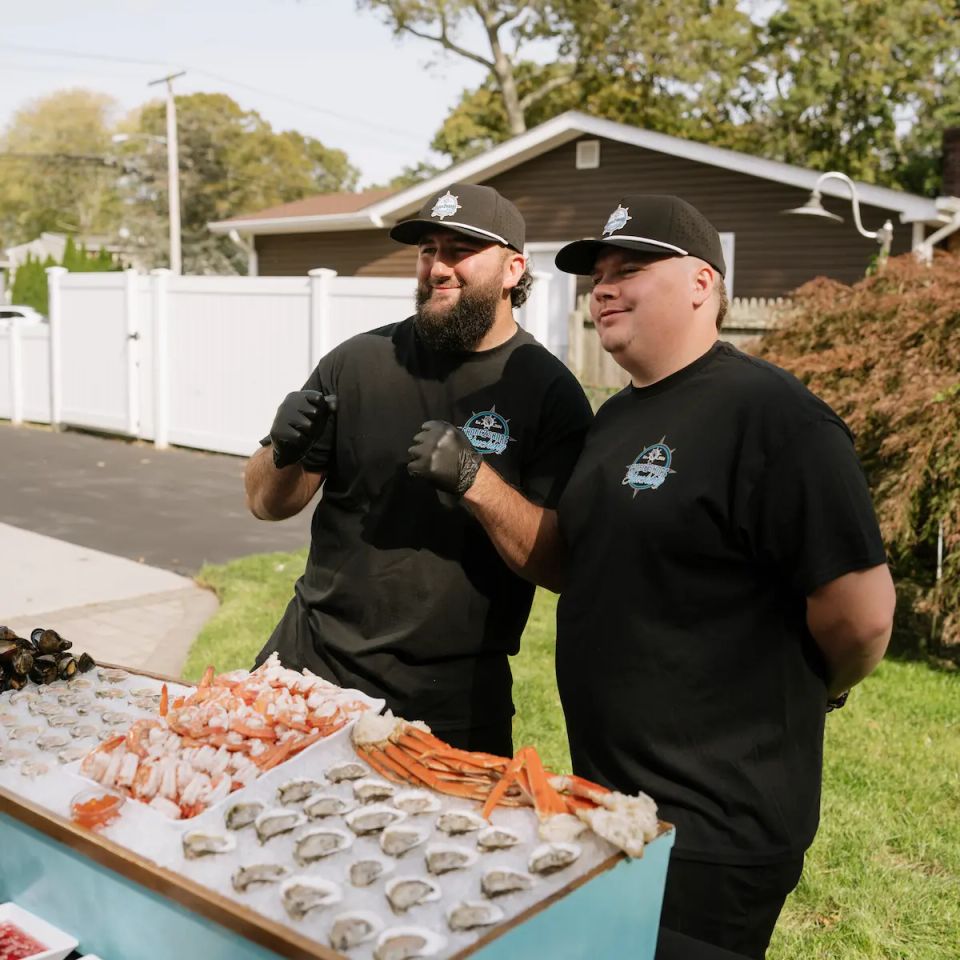 Sean and Mike, the owners of Shore2Shore Shucking, posing for a photo behind their raw bar.