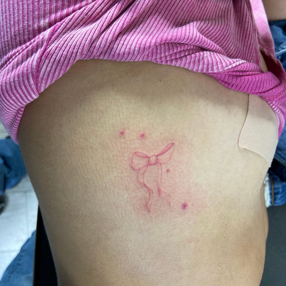 Image of a woman showing her delicate and pink tattoo on her right side