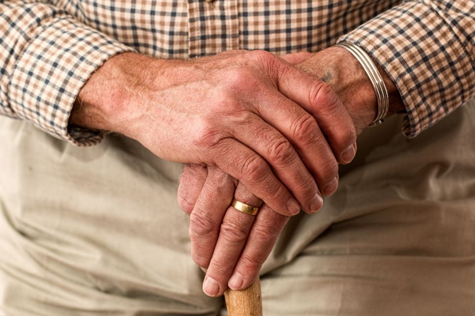 An elderly man's hands resting on a cane, representing senior independence and proactive falls reduction care.